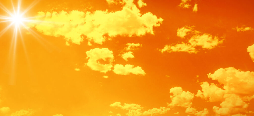 Bright glowing sun on orange sky background with clouds, horizontal. heat wave