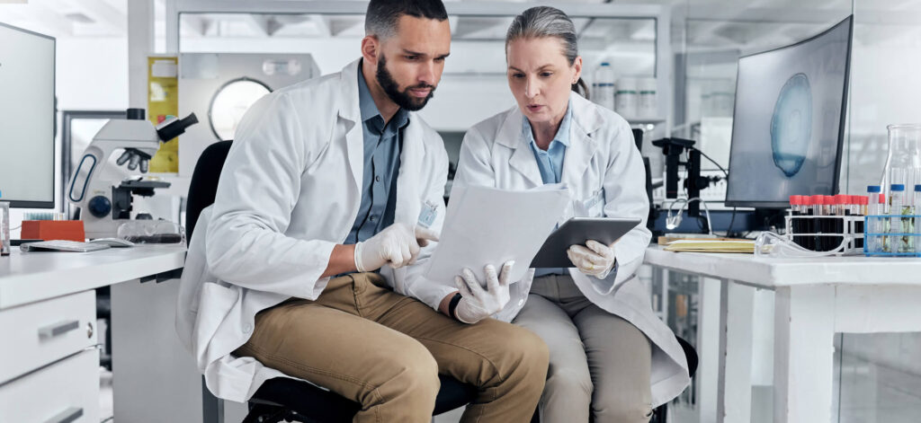 Two scientists reading a report and interpreting the results, helping a patient understand their pathology report