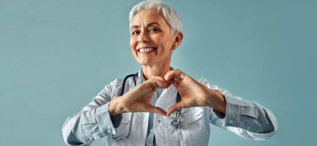 Woman smiling, holding hands up in a heart shape