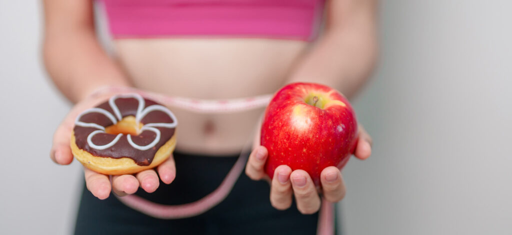 Person choosing between two food options, donut and apple