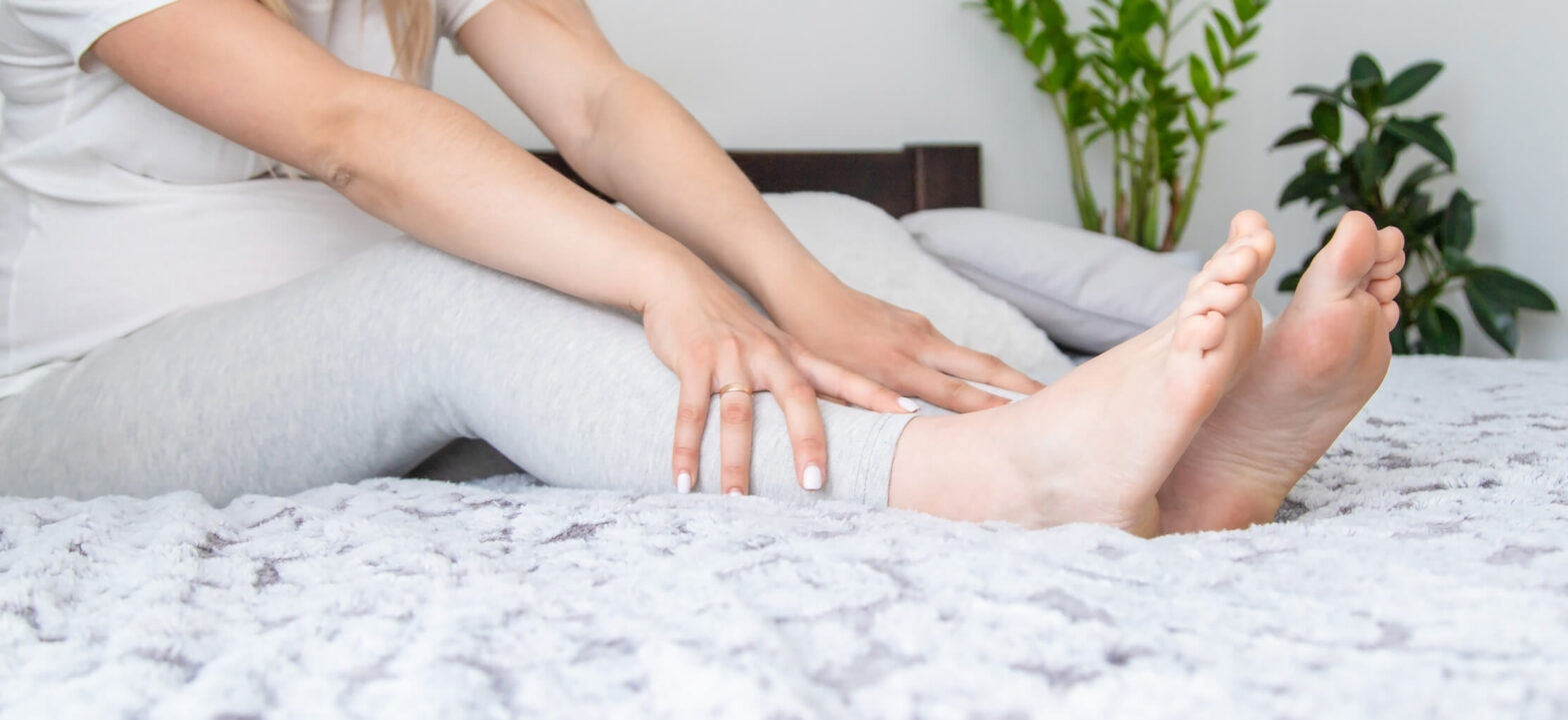 Woman massaging leg in bed, CKD night cramp