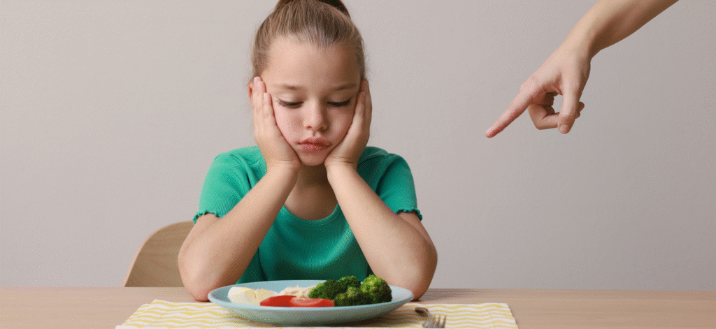 kid eating broccoli with someone pointing at their food