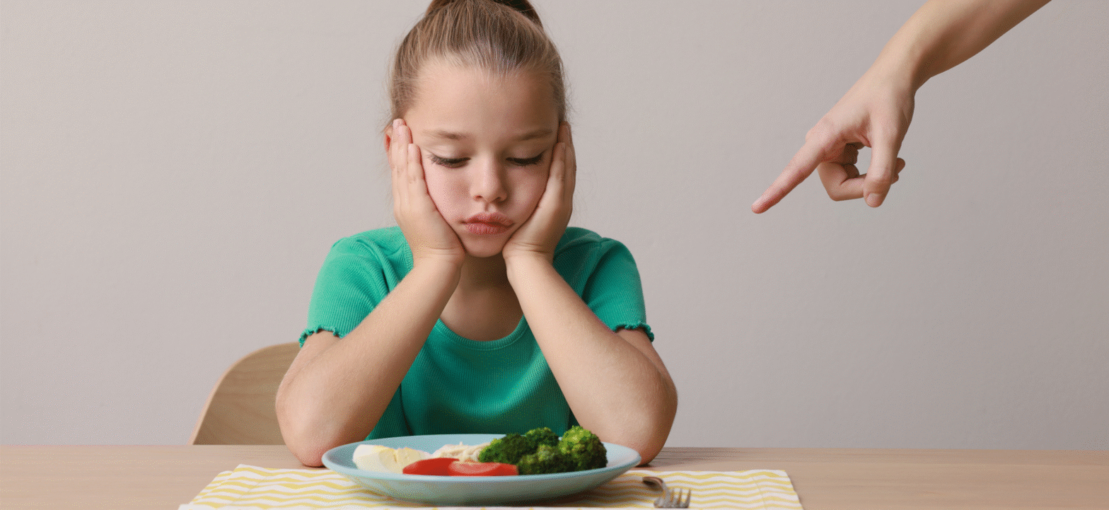 kid eating broccoli with someone pointing at their food