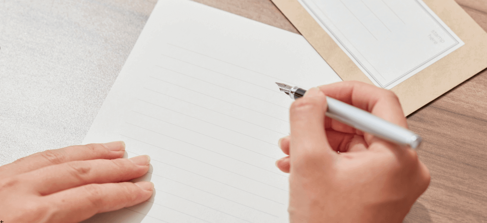 blank letter paper with someone holding a pen appearing to start writing