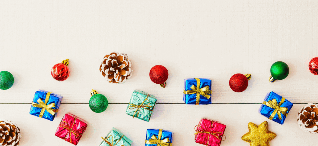 little wrapped holiday gift boxes, green and red round ornaments on a beige background