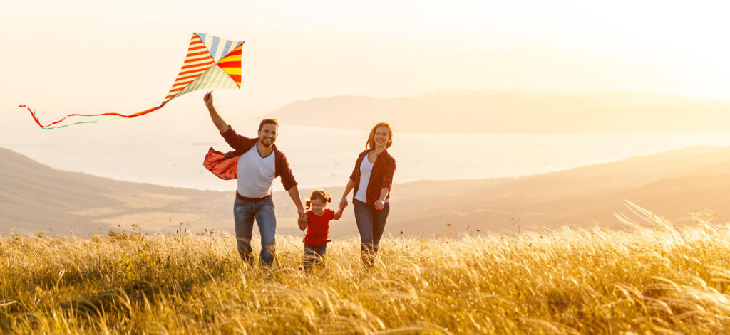 Parents playing outside with child, playing with a kite