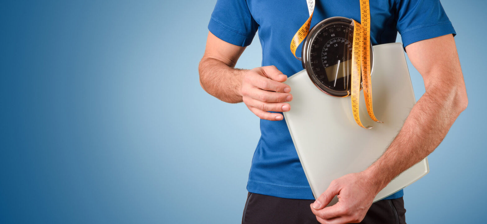 Man holding a scale, weight loss tips, winter weight harder to lose in the spring