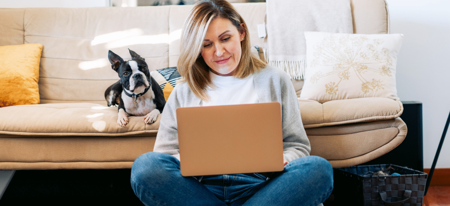 woman working on computer sitting next to dog
