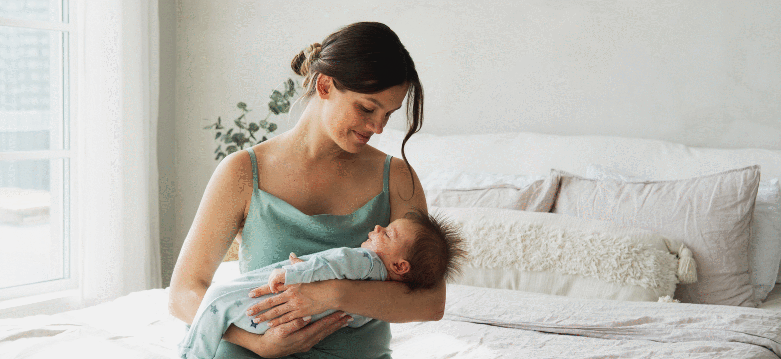 mom lovingly looking her baby while sitting on her bed
