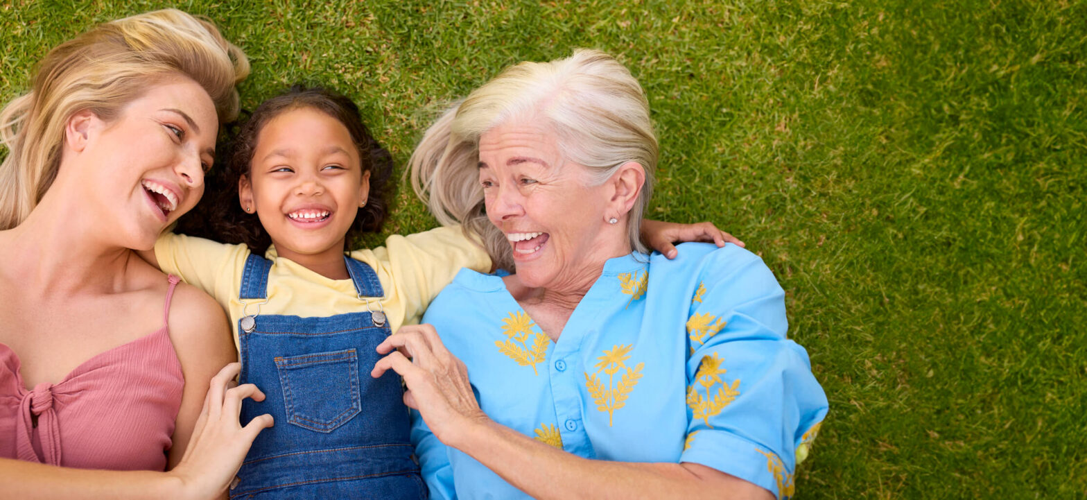 Multi-generational family laughing and having fun in a field. Sandwich generation