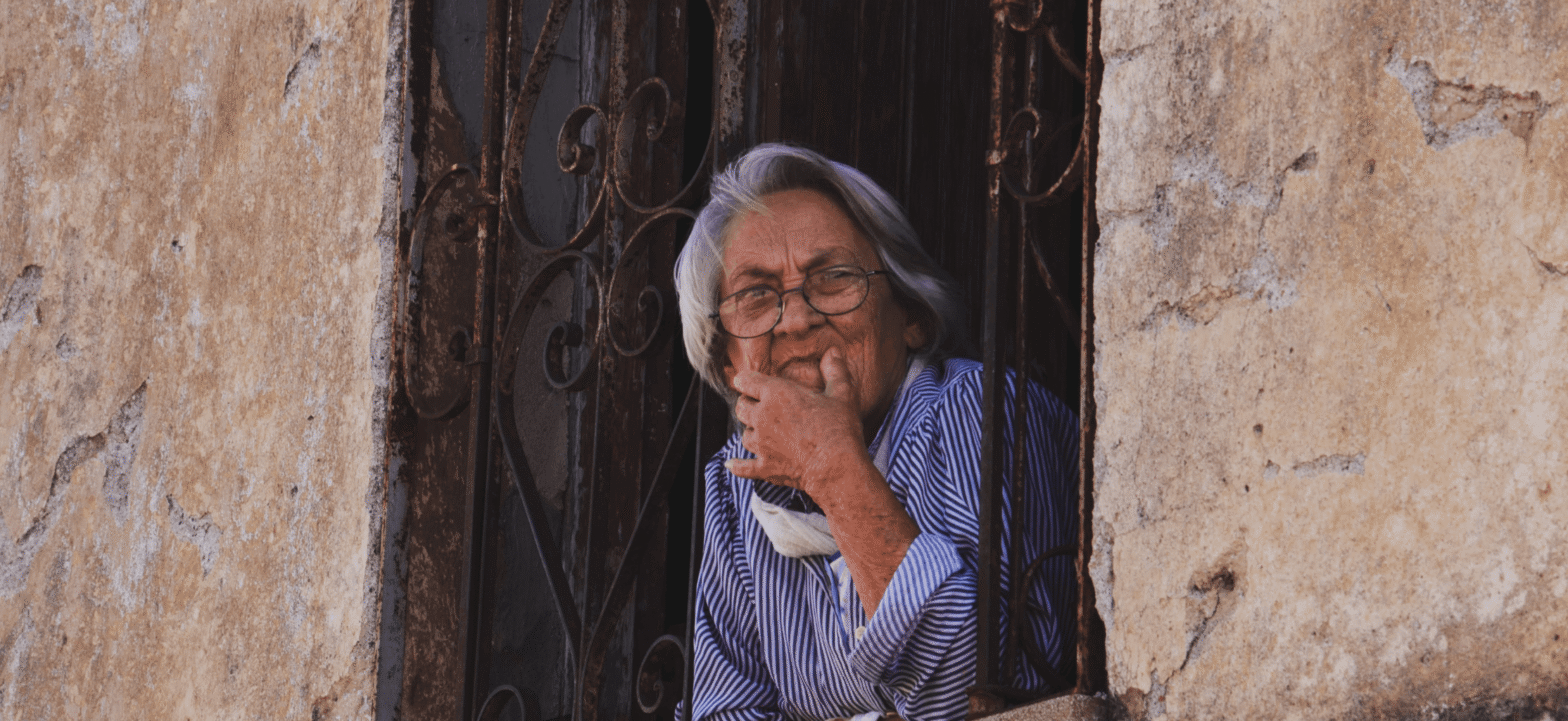 older woman with head out the window looking curiously outside